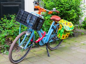 一辆带牛奶箱和蹦极绳筐的蓝色自行车。
