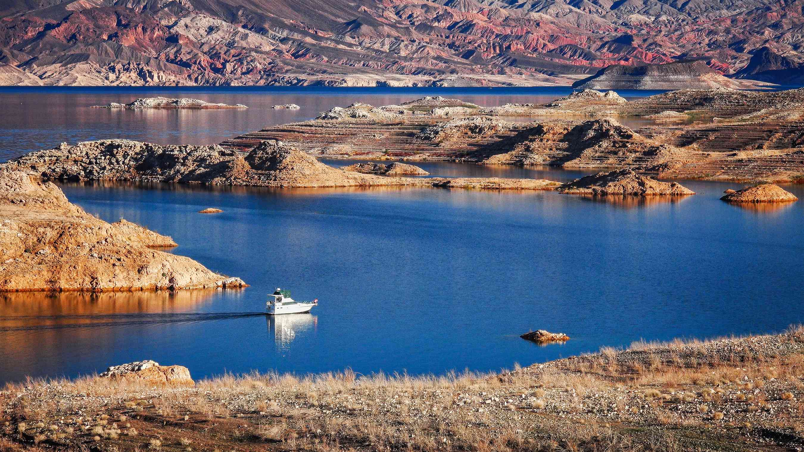 一艘船在沙漠环境下穿越蓝色的湖泊beplay体育官网电脑