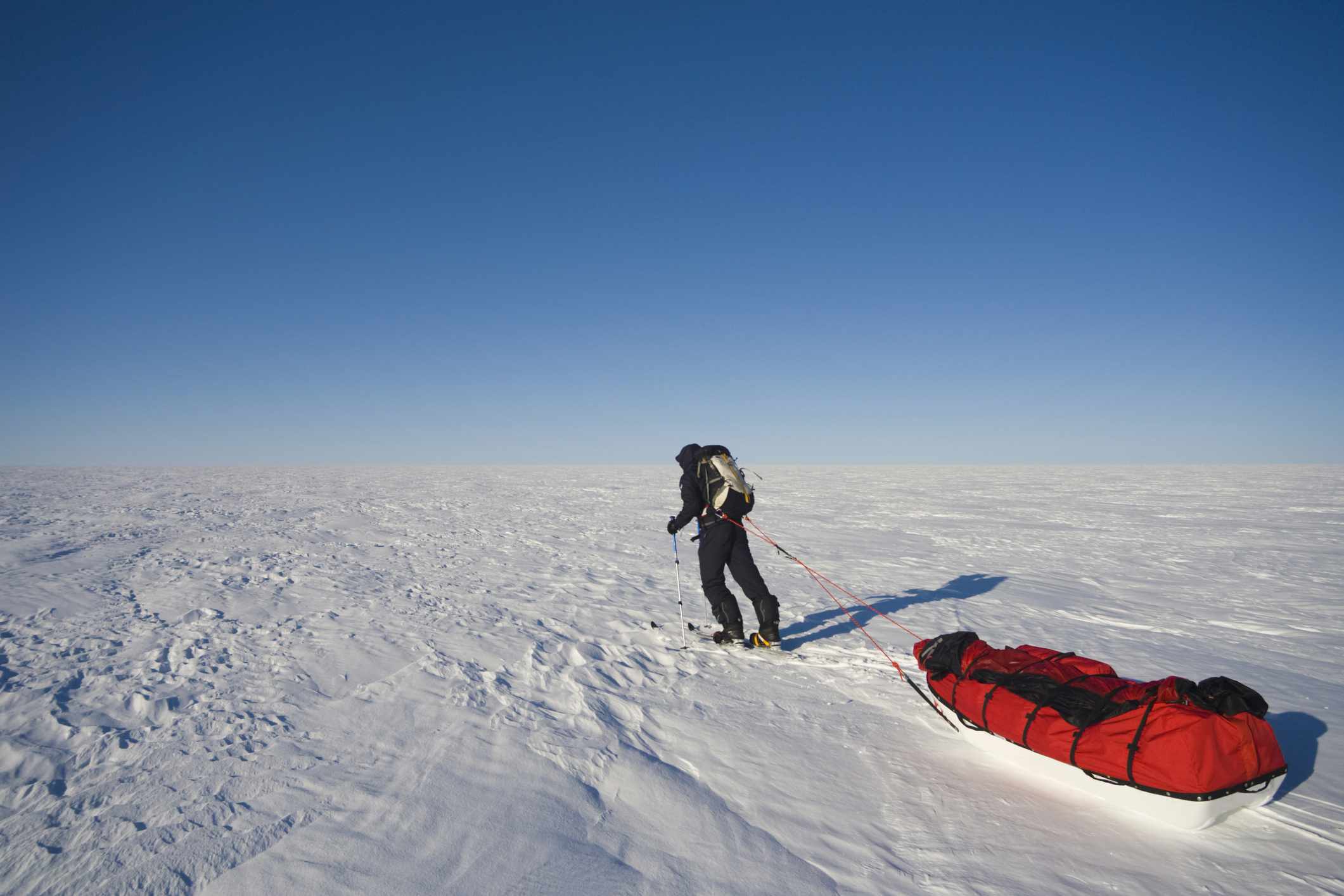 一名研究人员将齿轮拉到巨大的积雪冰盖上。“width=