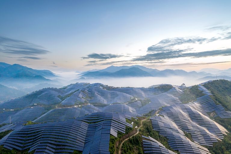 一座宏伟的太阳能发电站坐落在雾气蒙蒙的山顶上＂class=