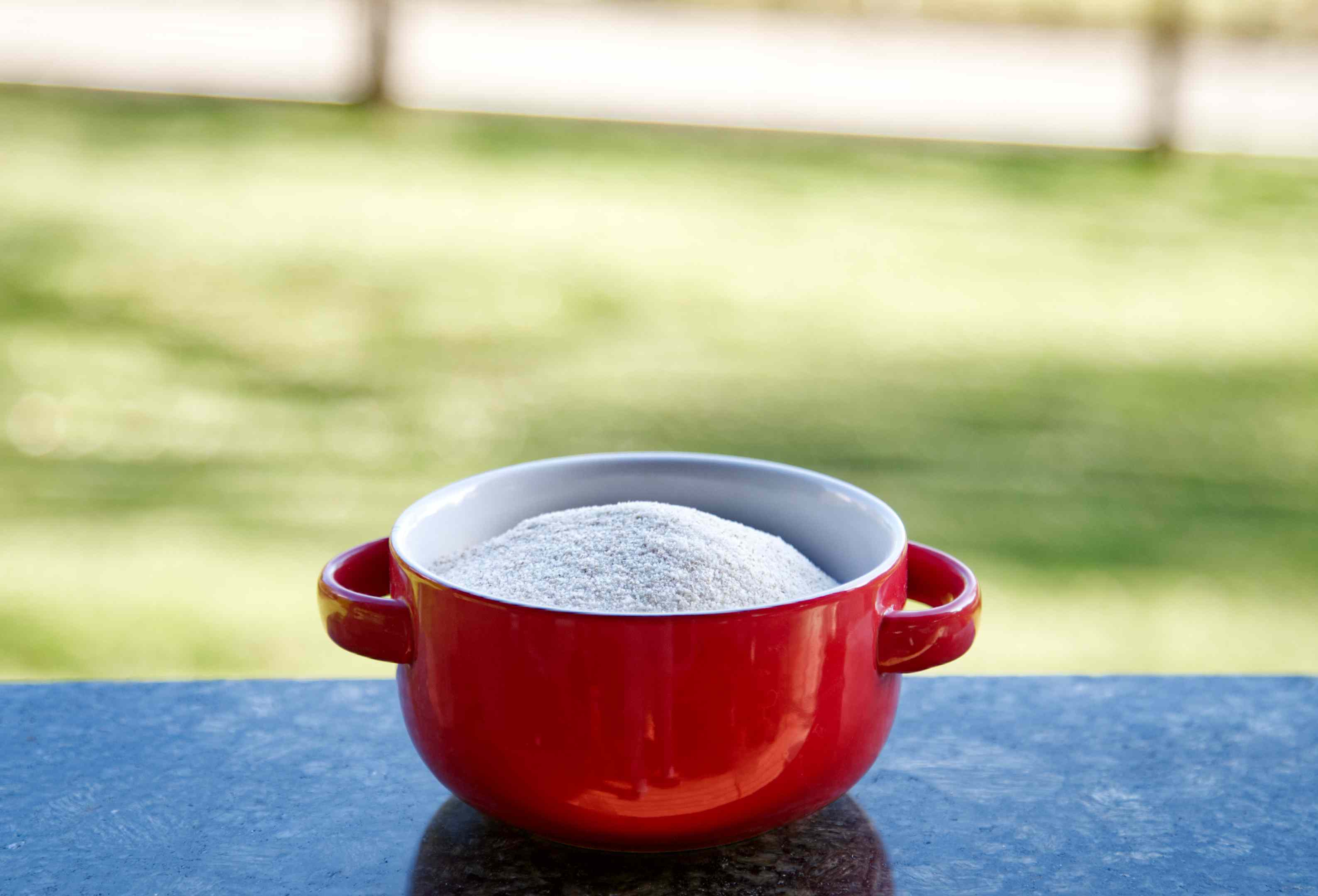 未煮的奶油小麦在红色陶瓷碗与把手外面花岗岩桌子