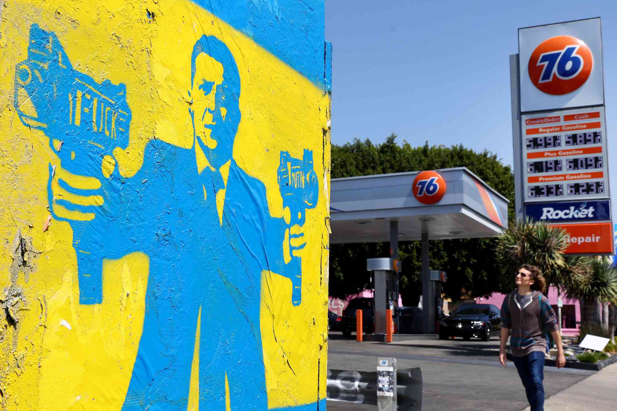 艺术家1Goodhombre的一条街道模具描绘了乌克兰总统沃罗迪米尔·泽伦斯基（Volodymyr Zelenskyy）抓着的冲锋枪，并于2022年3月30日在加利福尼亚州洛杉矶的右边有加油站。在俄罗斯入侵乌克兰之后，天然气价格大大上涨。根据美国人口普查局的数据，加利福尼亚是乌克兰血统的约112,000居民的所在地。“width=