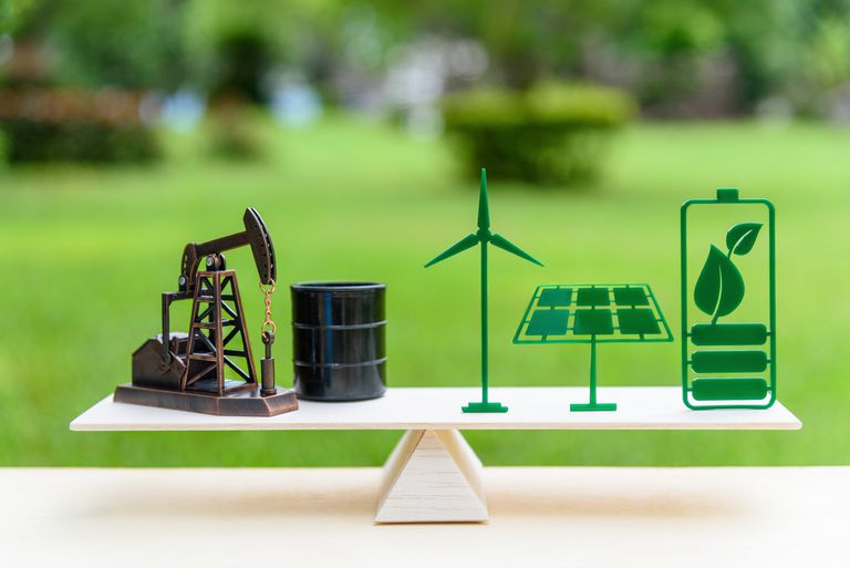 化石燃料vs可再生/未来清洁替代能源概念:石油抽油机、原油桶桶、太阳能电池板、绿叶电池、风力涡轮机在木天平上处于同等位置。＂class=