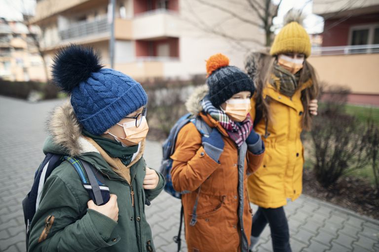 孩子们在冬天走上学校“class=