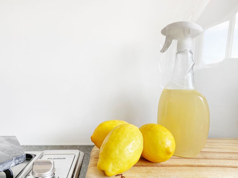 台面上装满了浅黄色液体的喷雾瓶旁边的3条柠檬