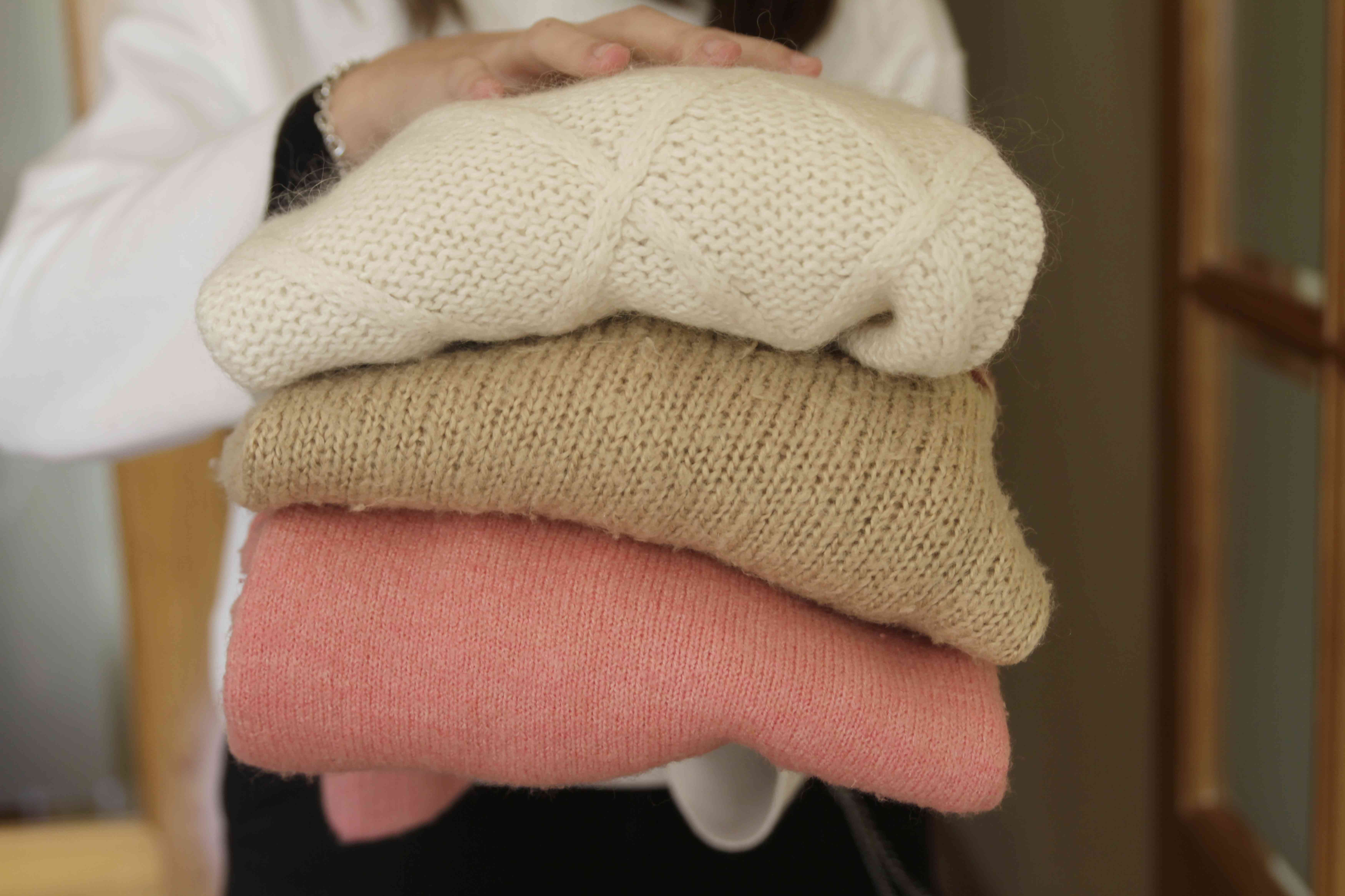 女人拿着一堆温暖的毛衣