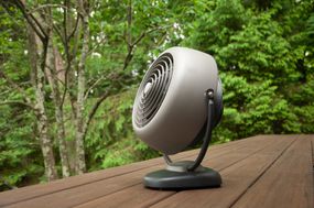 retro-looking gray fan outside on wooden deck in woodsy backyard