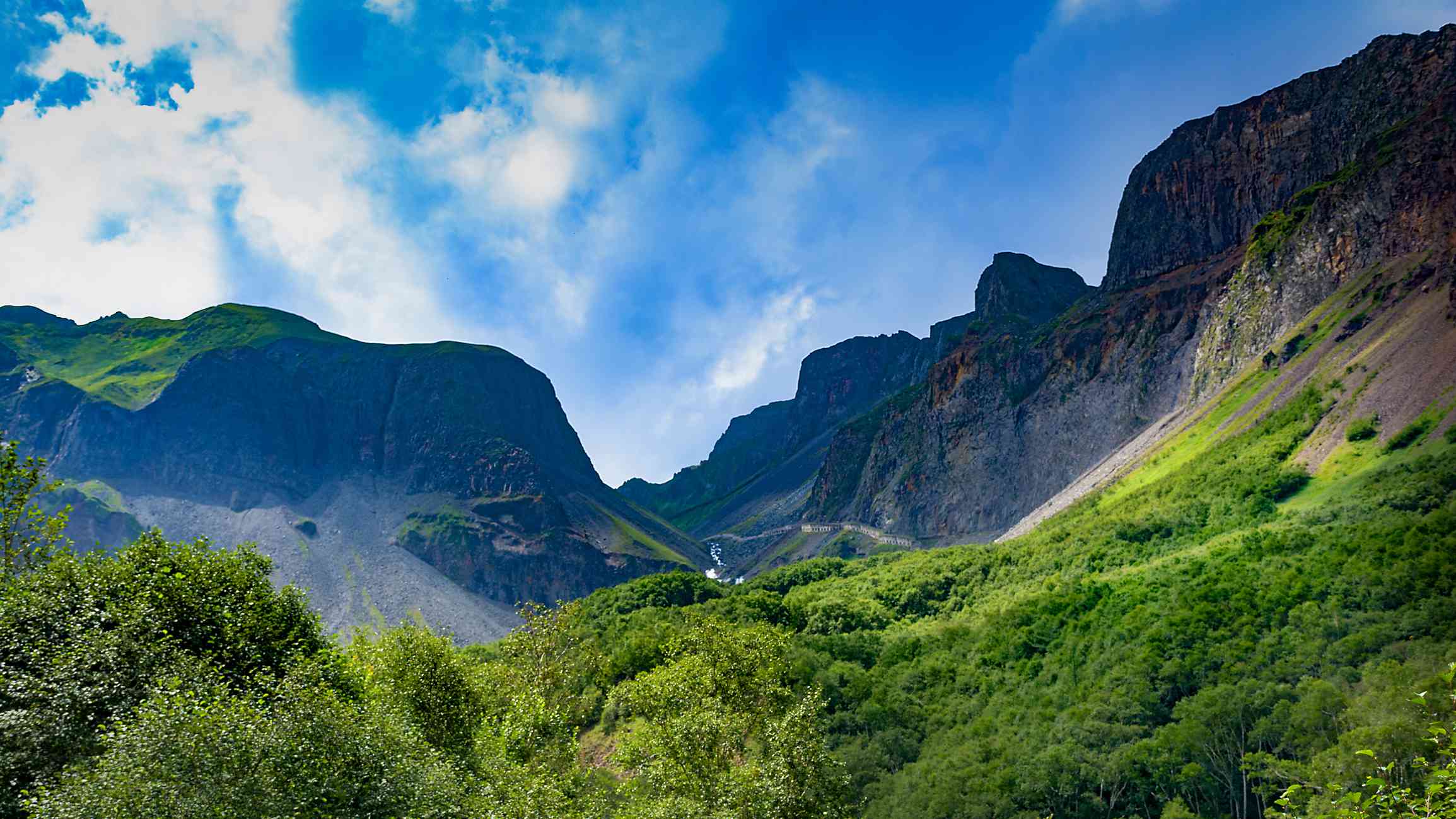 高耸的岩石峭壁下的森林山谷和蔚蓝的天空