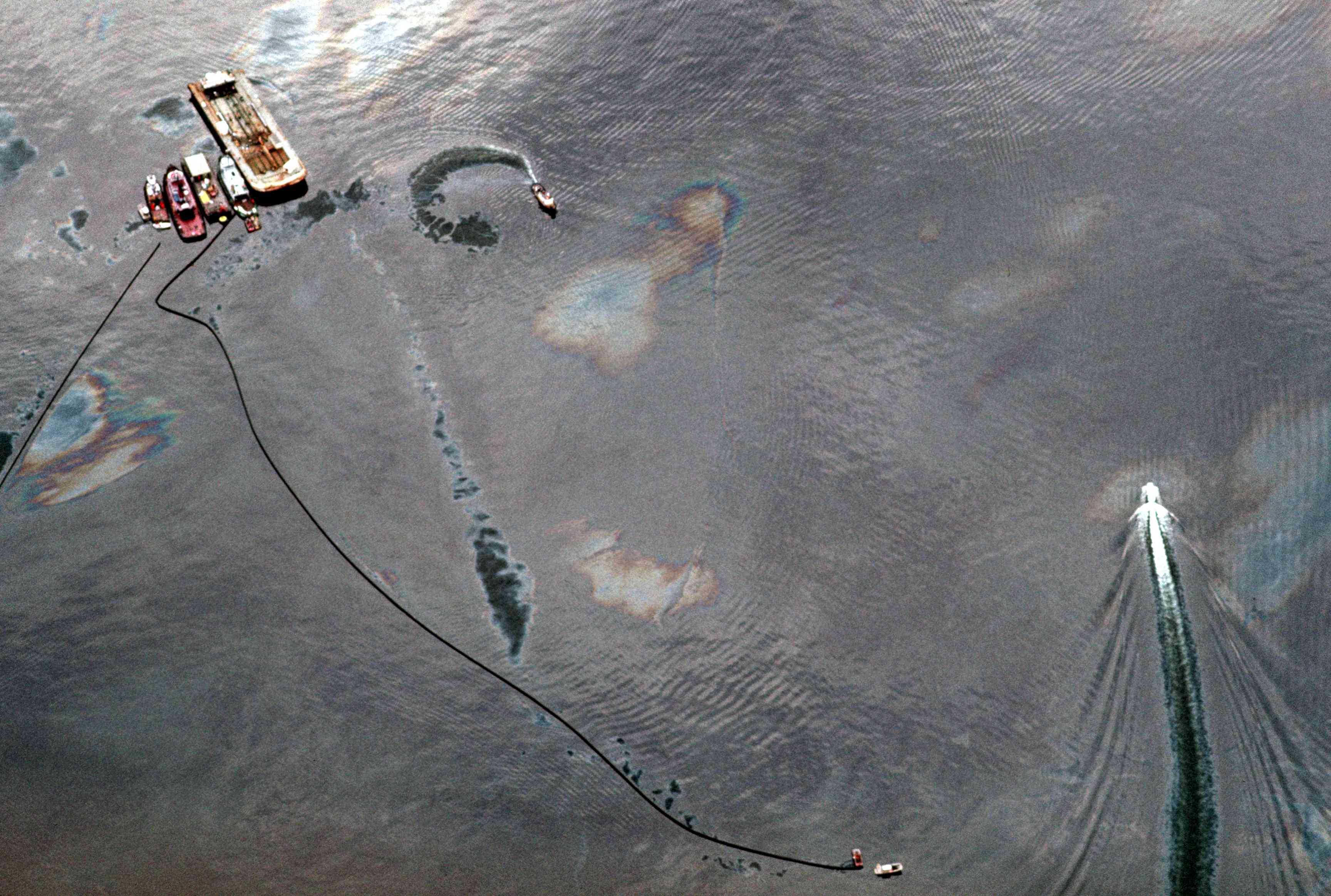 在美国阿拉斯加州威廉王子湾，船只和吸油栅在埃克森瓦尔迪兹号石油泄漏事故周围盘旋，以控制浮油扩散＂width=