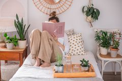 女人在床上读书，被各种植物包围着椅子和托盘