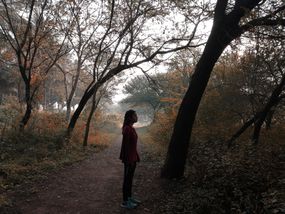 一个女人站在树林中间，看起来迷路了