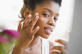 黑人女性穿上脸乳液——库存图片