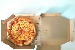 头顶上的一张油腻的披萨放在有油渍的纸盒里