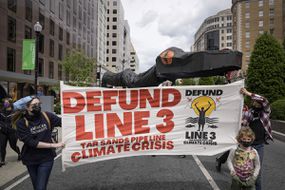 beplay体育官网电脑2021年5月7日，环保人士在华盛顿特区举着一条巨大的蛇管道抗议安桥3号线石油管道。