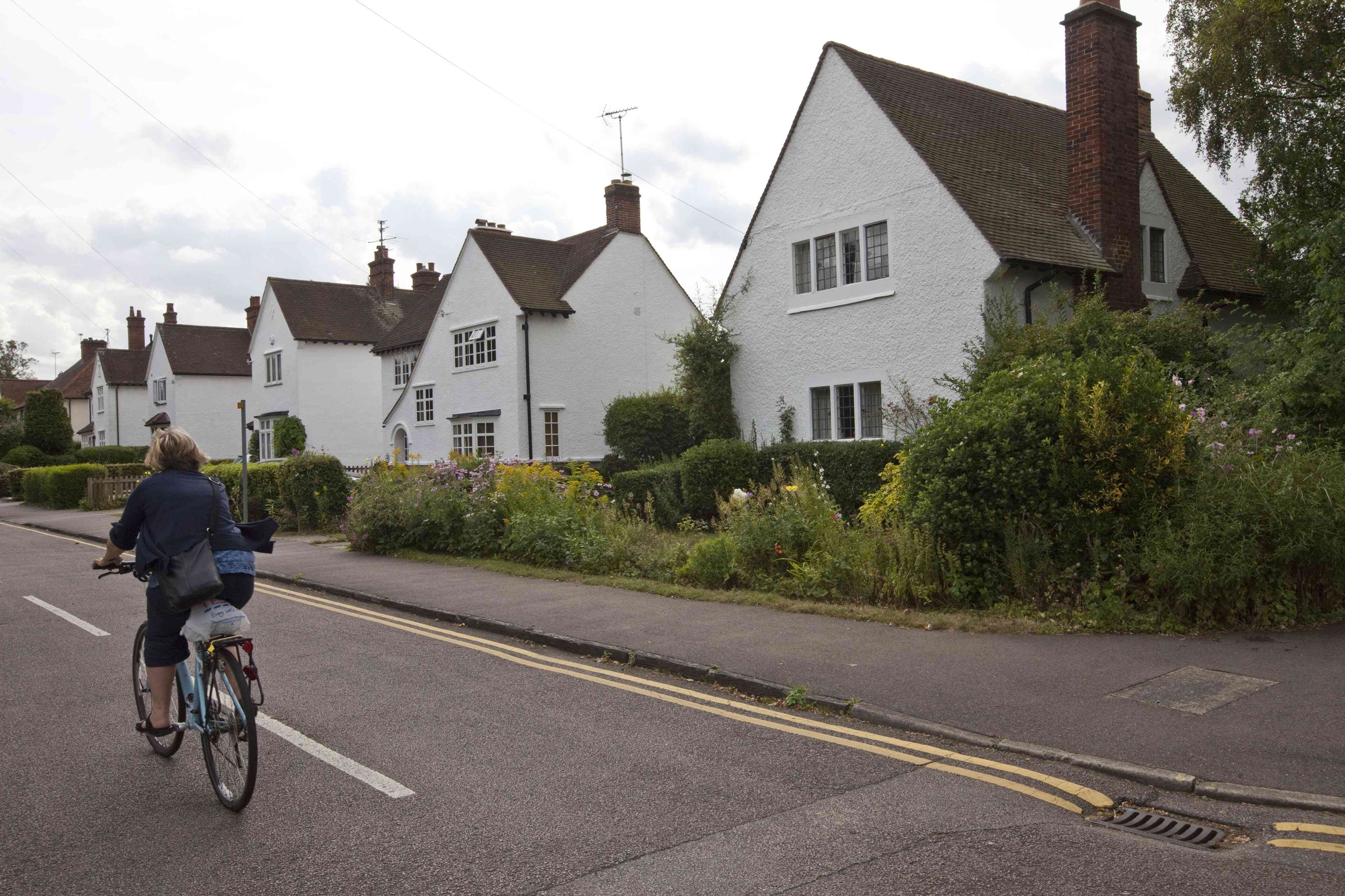 英国 -  Letchworth Garden City  - 一个女人循环她的自行车过去艺术和工艺品时期的房子