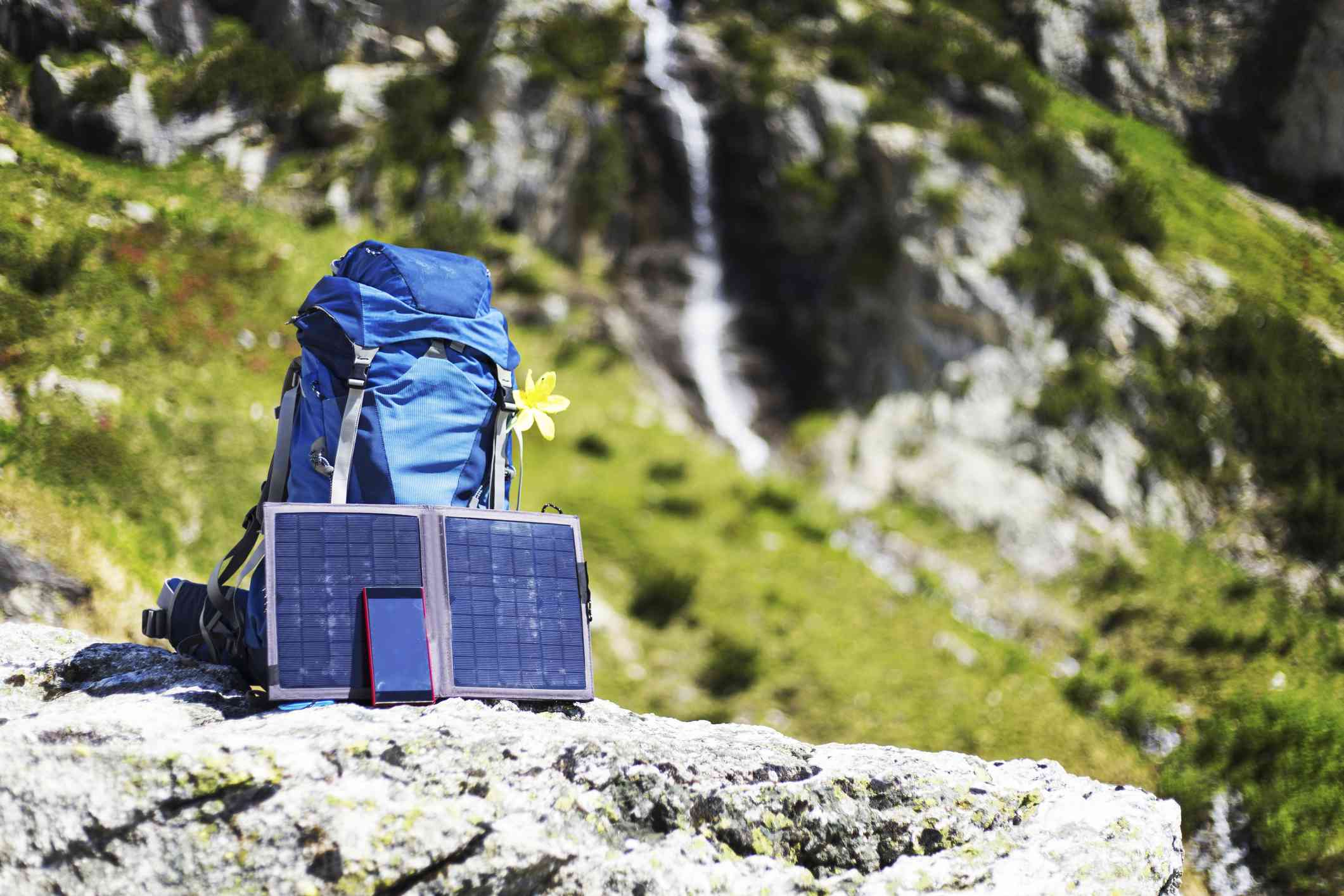 悬崖边上的一个装有便携式太阳能板的背包＂width=