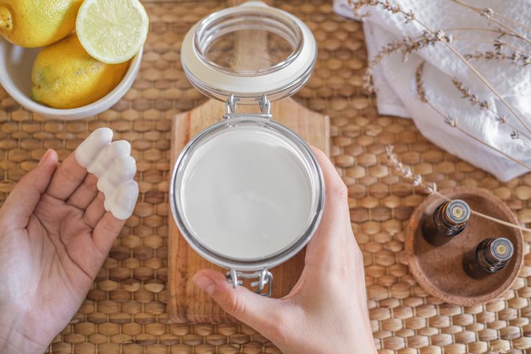 自制酸奶面膜在玻璃容器中，双手涂上白色混合物