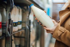 妇女的特写镜头，拿着一瓶有机新鲜牛奶在超市
