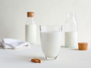 玻璃杯和瓶子的牛奶和生杏仁放在桌子上