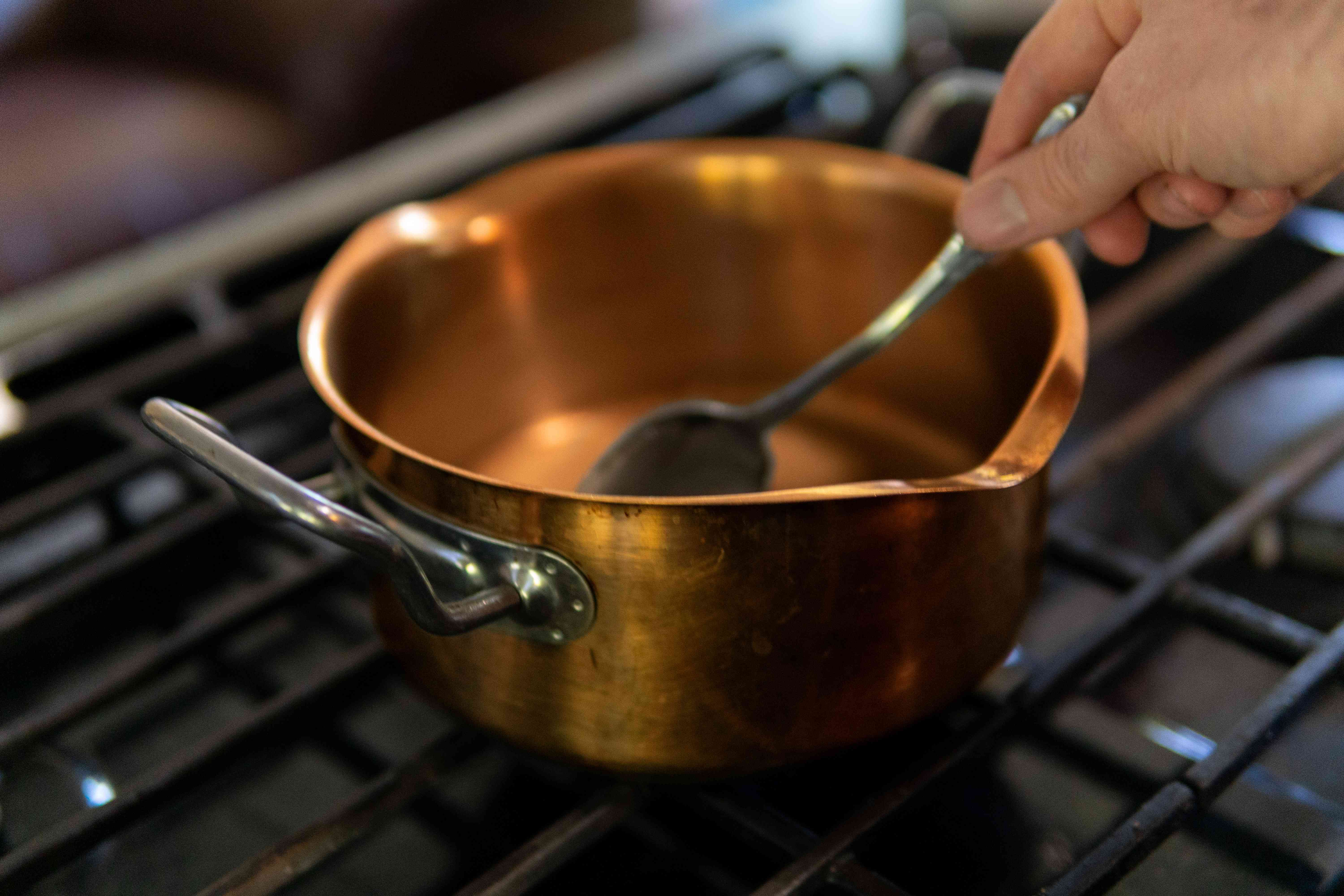 手在炉子上用铜碗做饭