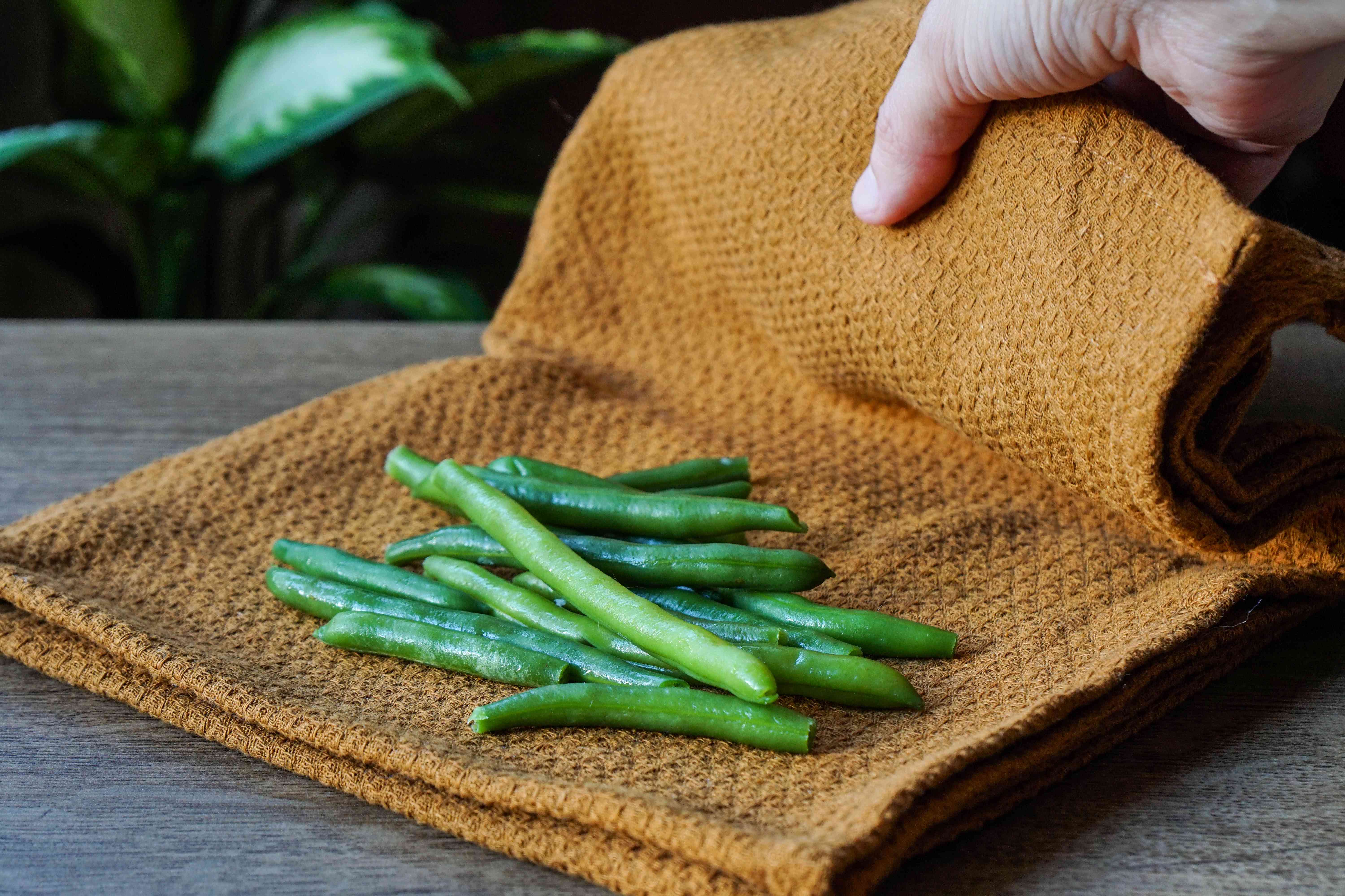 新鲜的四季豆被放置在潮湿的棕色织物中，以便无塑料储存