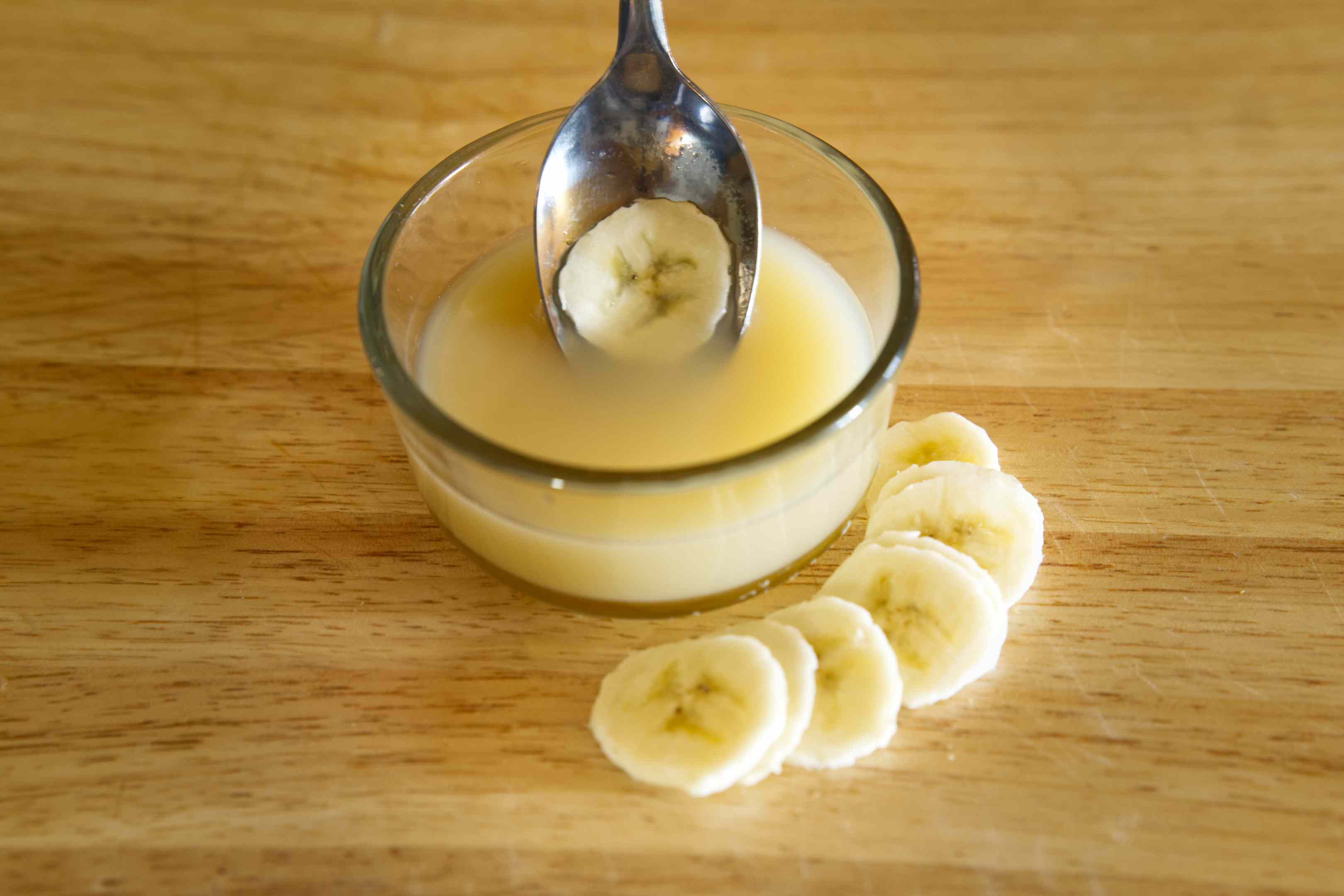 用勺子蘸香蕉片到盛满柠檬水的玻璃碗里，防止变色
