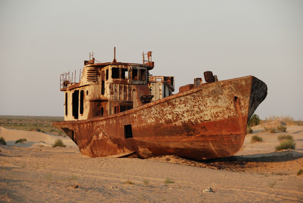 一艘锈迹斑斑，被遗弃在曾经是湖泊的沙漠里的船