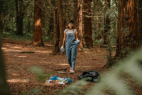 一个穿工作服的女人在森林里捡垃圾。