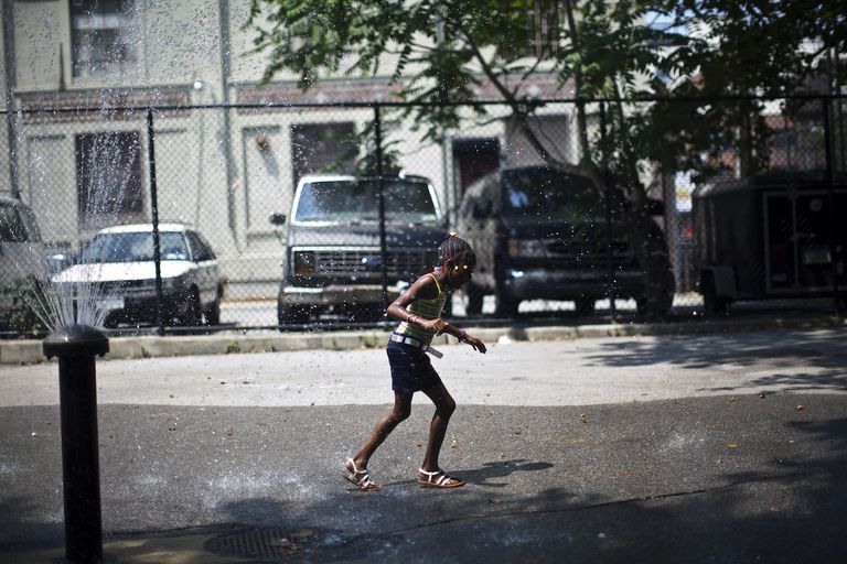 在纽约布鲁克林区，一个女孩跑过一个饮水机来降温