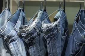 A row of jean hanging on hooks.