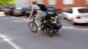一个男人骑着一辆带有两个小孩的人骑着头盔的人骑自行车