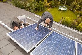 技术人员安装太阳能照片伏打板在Ambleside房子屋顶,英国坎布里亚郡。”width=