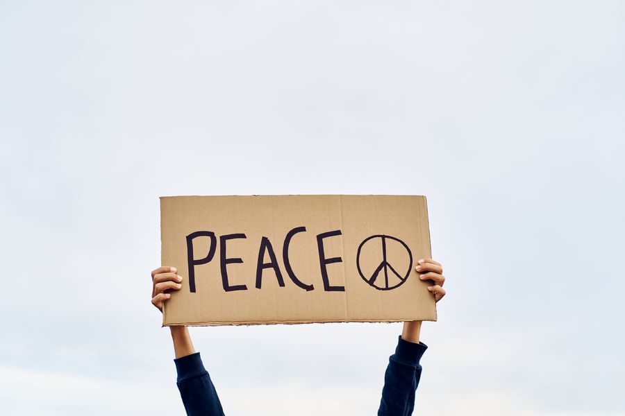 两只手举着自制的“和平”和写在纸板上的和平标志。