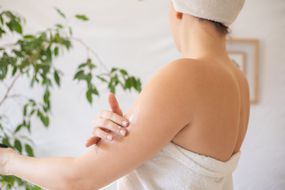 女人裹着白毛巾浴后乳液适用于湿润剂