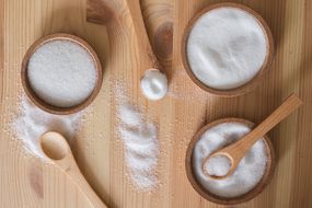 木制的碗和勺子装满了不同种类的白糖