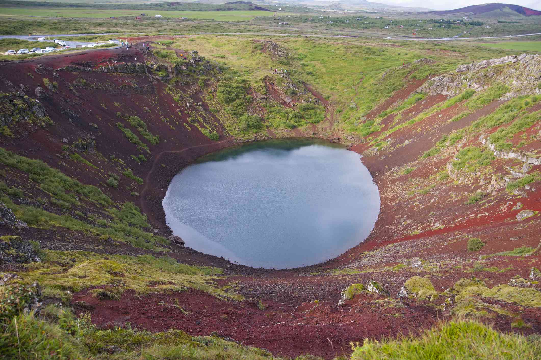 宽阔的火山口湖，山坡上有鲜红色的岩石和浅绿色的苔藓