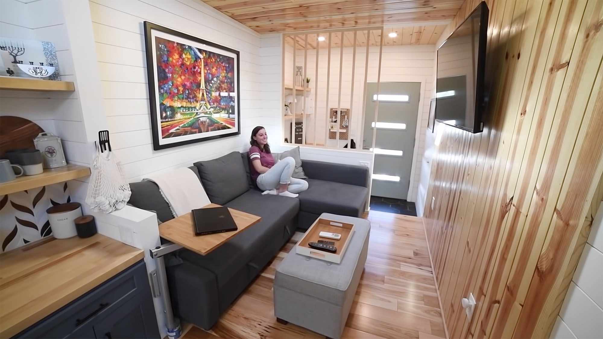 悉尼·金设计的一间小房子的内部，金子坐在电视机前的灰色沙发上。
