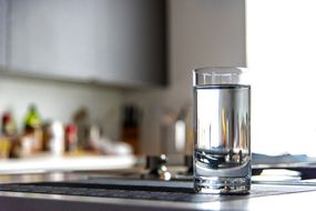 一杯水放在厨房柜台上＂width=